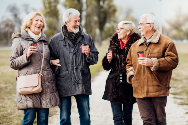 Two older couple walk along a path in a park together