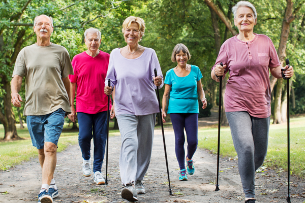 A group of individuals in mid- to late life walking together on a nature trail.