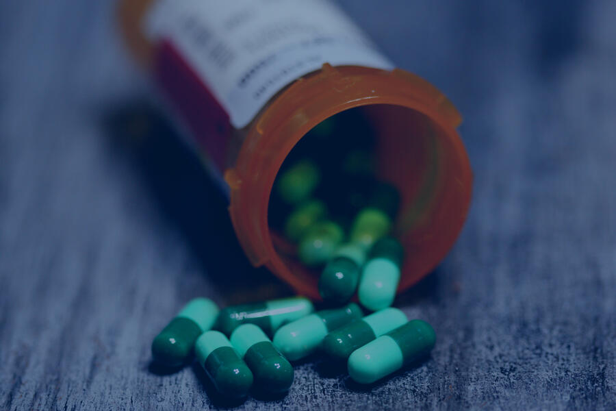 An open pill bottle lies on a table