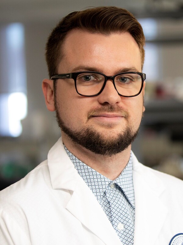 Dr. Thomas Prevot stands in a lab wearing a lab coat