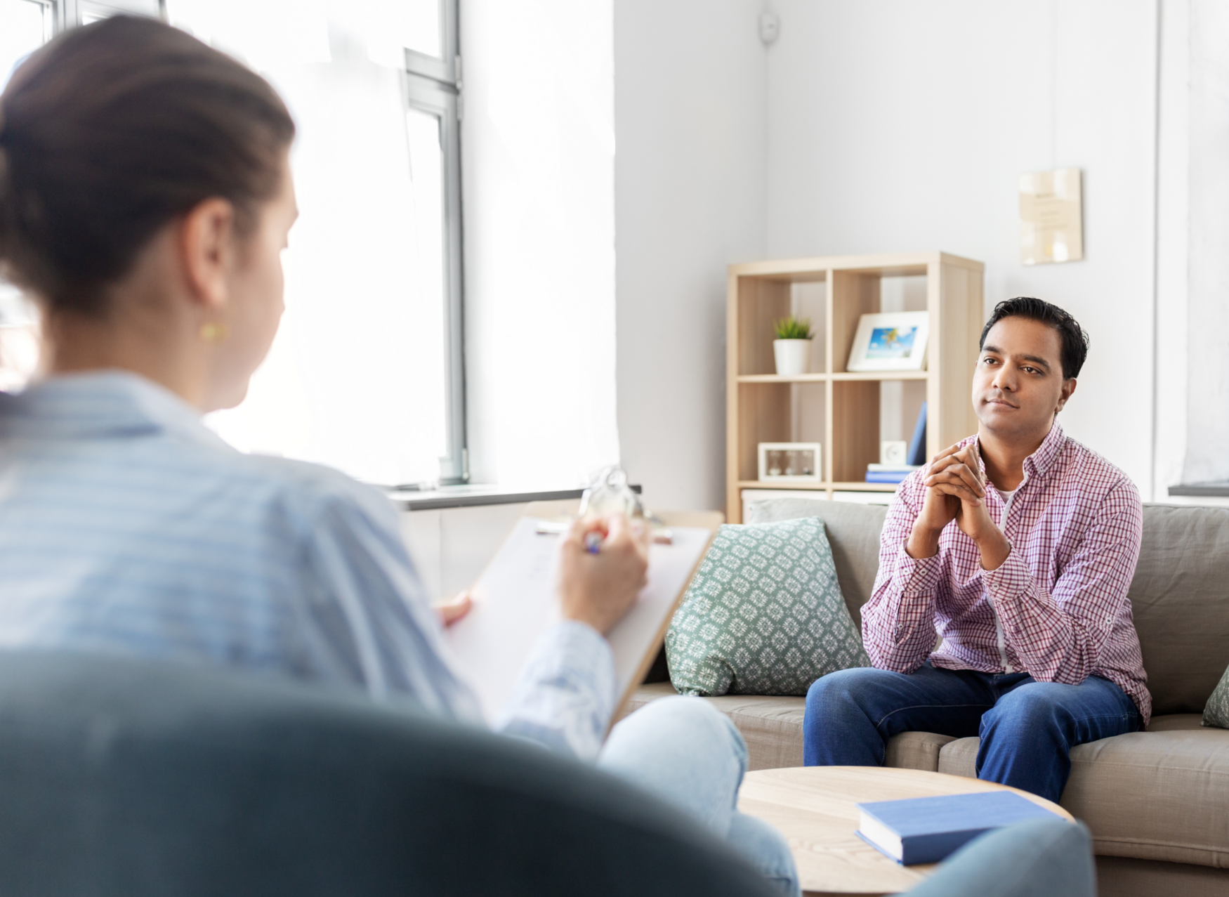 A man sits across from a therapist in a brightly lit room