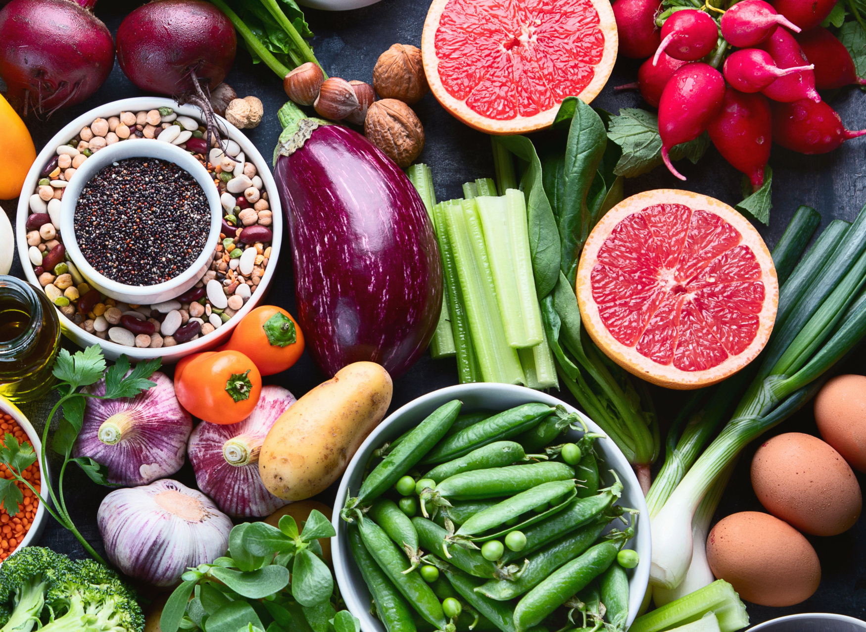 A selection of food, including green beans, grapefruit, potatoes, celery, and legumes, laid out on a table.