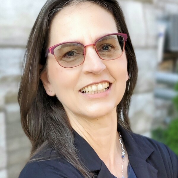 Dr. Zoe Hilton standing outside in front of an old stone building, smiling